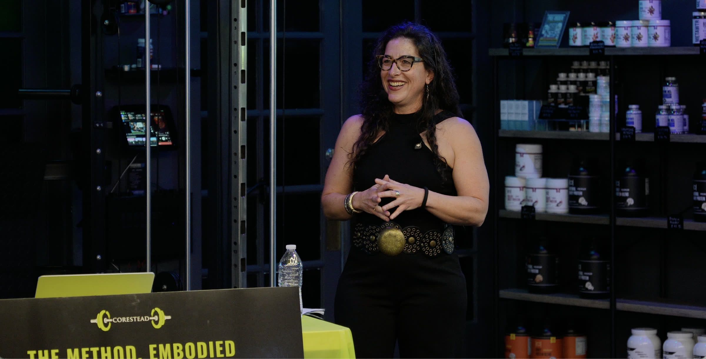 Emily Frydrych smiling mid-sentence while presenting a Corestead keynote on the gym floor