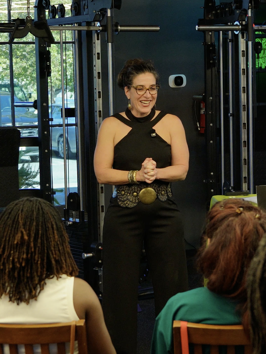 Emily Frydrych leading a Lifting From Within workshop, speaking to seated participants on the gym floor